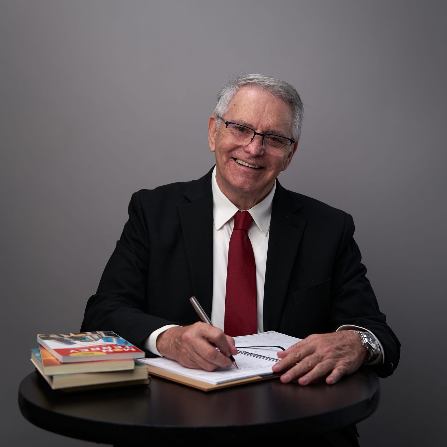 Adolfo Siller escribiendo junto a sus libros